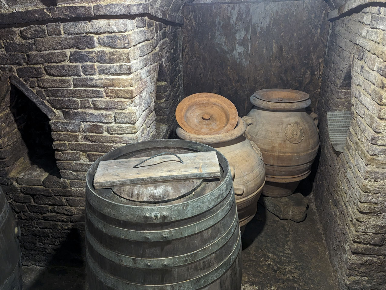 A wooden barrel and some large ceramic vases in the cellar