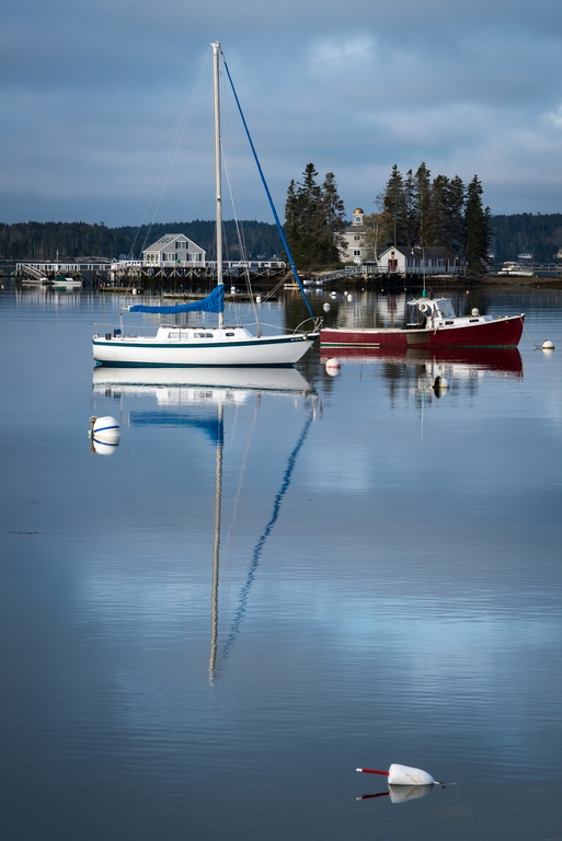 Sailboat and clouds reflected in water