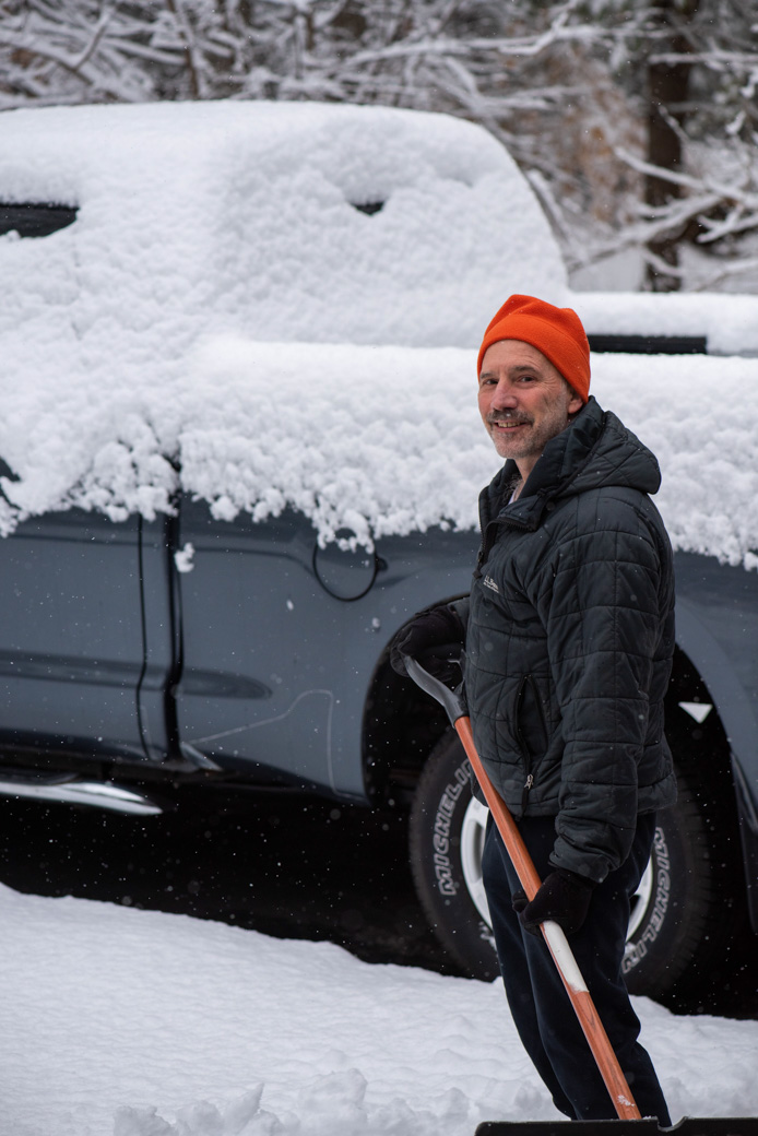 Paul standing in front of the truck while shoveling snow