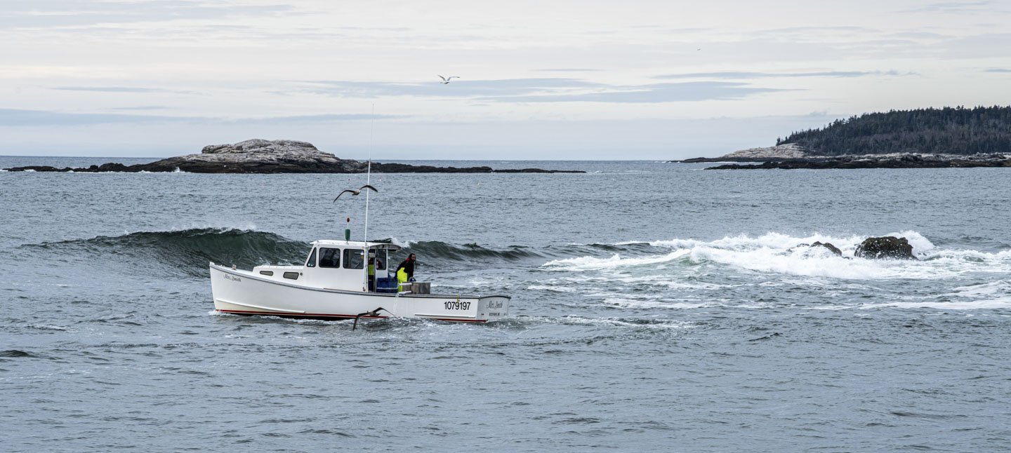 A wave about to break, seen behind a lobstering boat