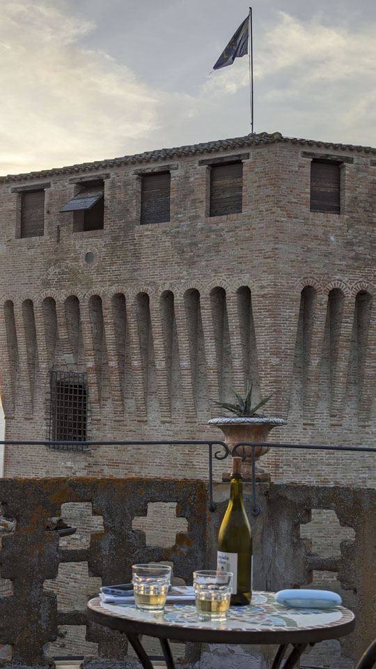 Small table with glasses of wine in front of a large Medieval fort