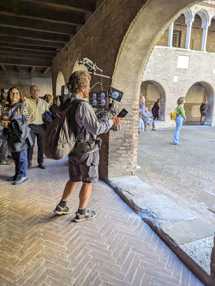 A man wearing a large backpack, plus a harness that is connected to a camera array.