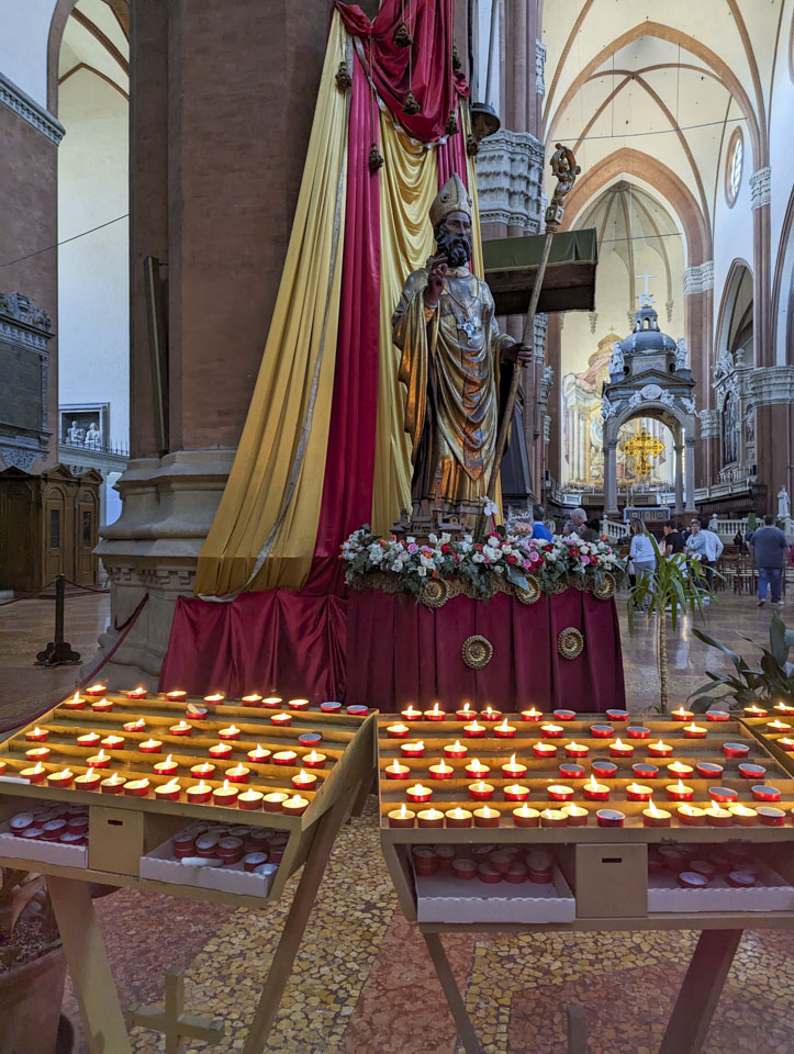 Two stands of votives in front of a statue of Saint Petronio