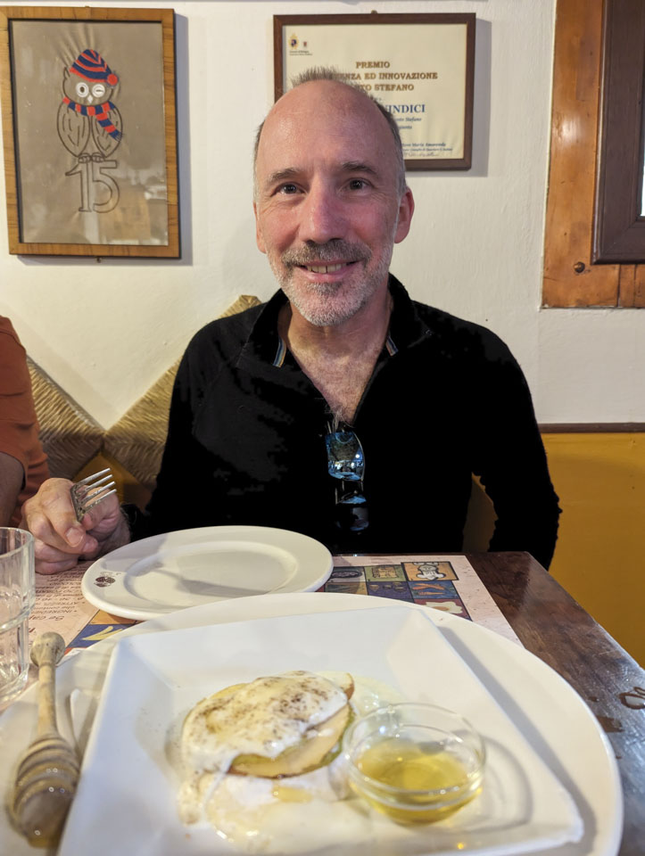 Paul in back of a blurry image of the cheese and pear dish.