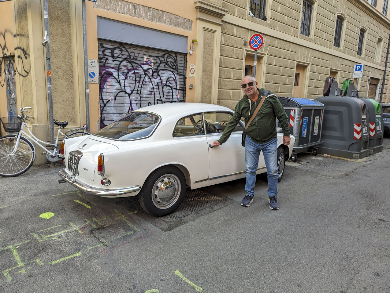 Francesco posing as if he was going to open the door to a vintage white car.