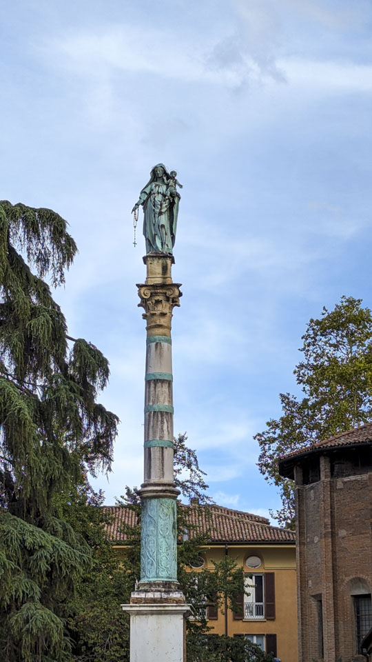 A tall column with a statue of Saint Mary holding a rosary.
