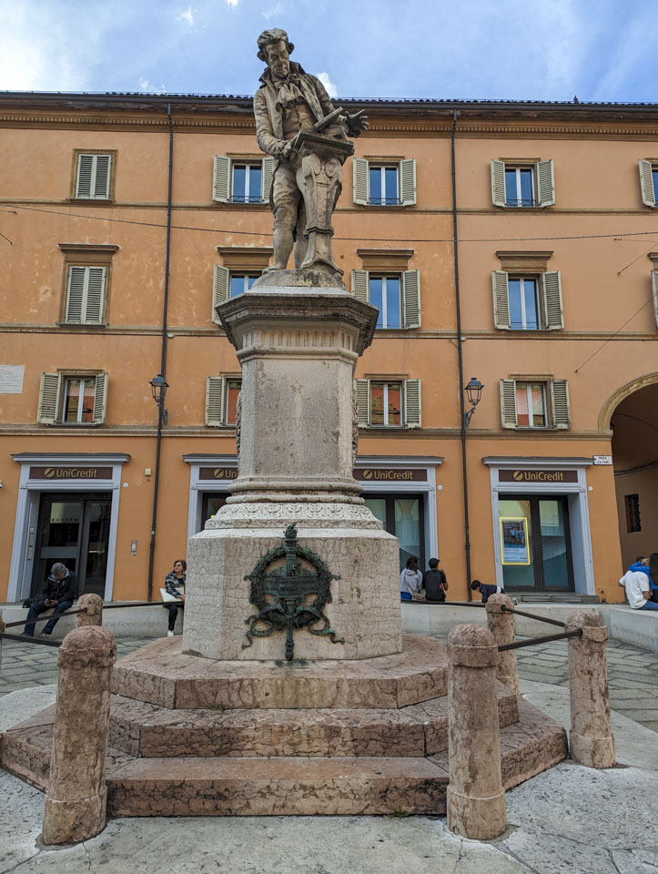 A statue of a man standing behind a small table with books on it.