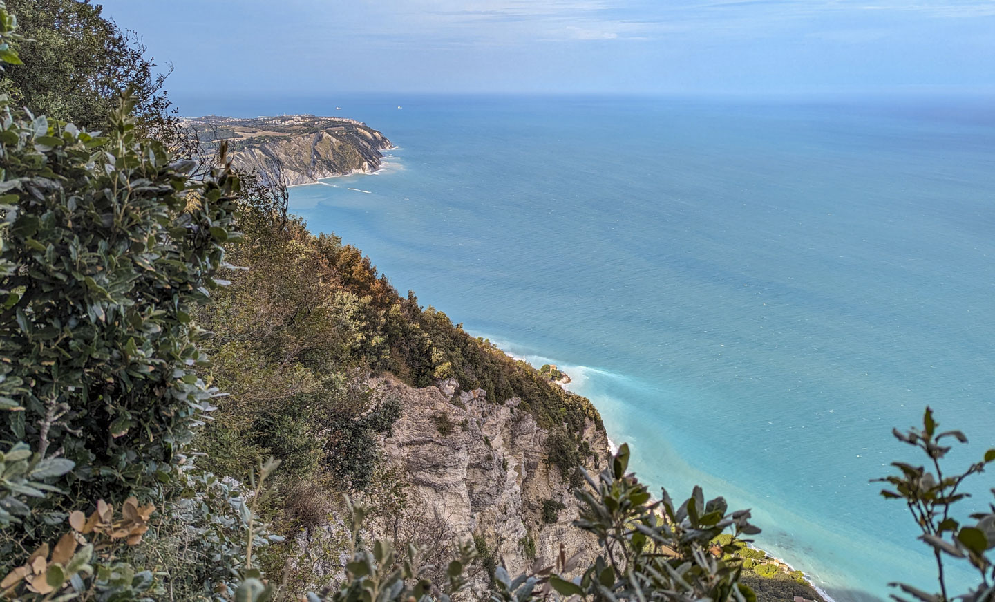 Steep terrain is on the left and the Adriatic Sea is on the right. Buildings can be seen in the distance on a high spit of land.