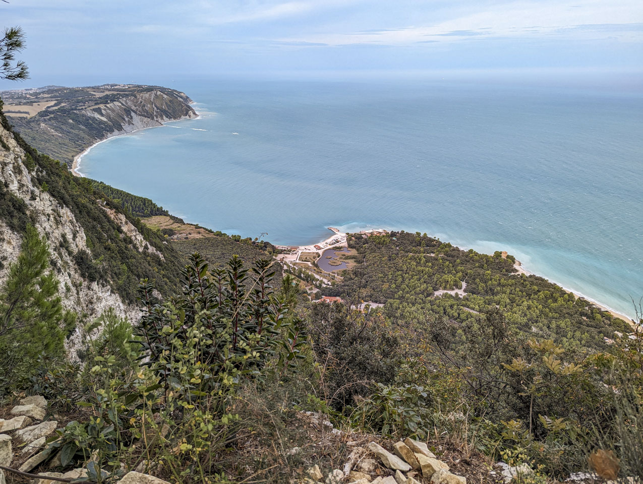 Steep terrain is on the left and the Adriatic Sea is on the right. Buildings can be seen in the distance on a high spit of land.