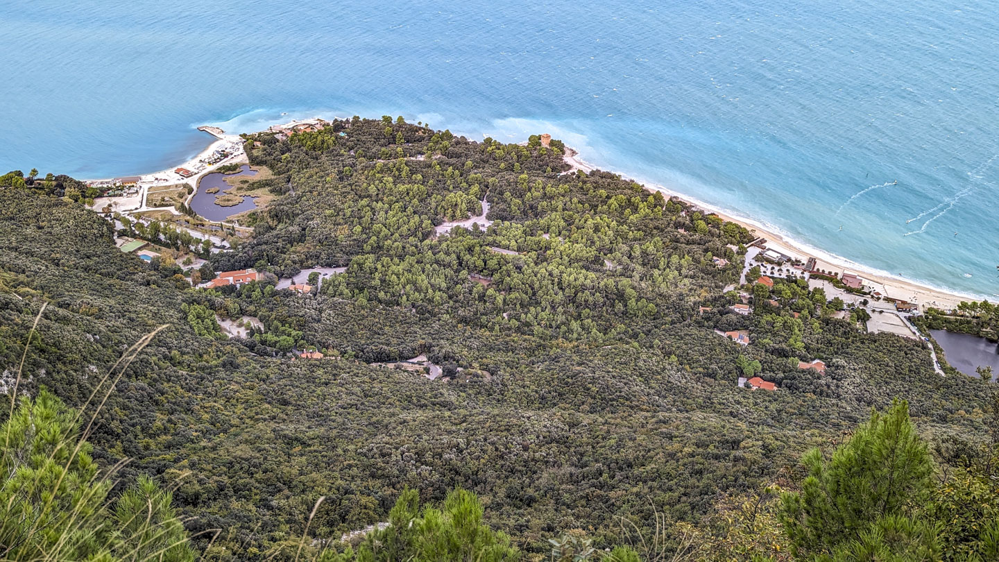 Looking down at a resort area. Much is covered with trees, and there are a few roads as well as scattered buildings.