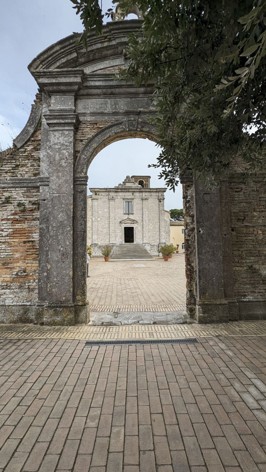 A photo directly through the arched entrance looking towards the blocky church.