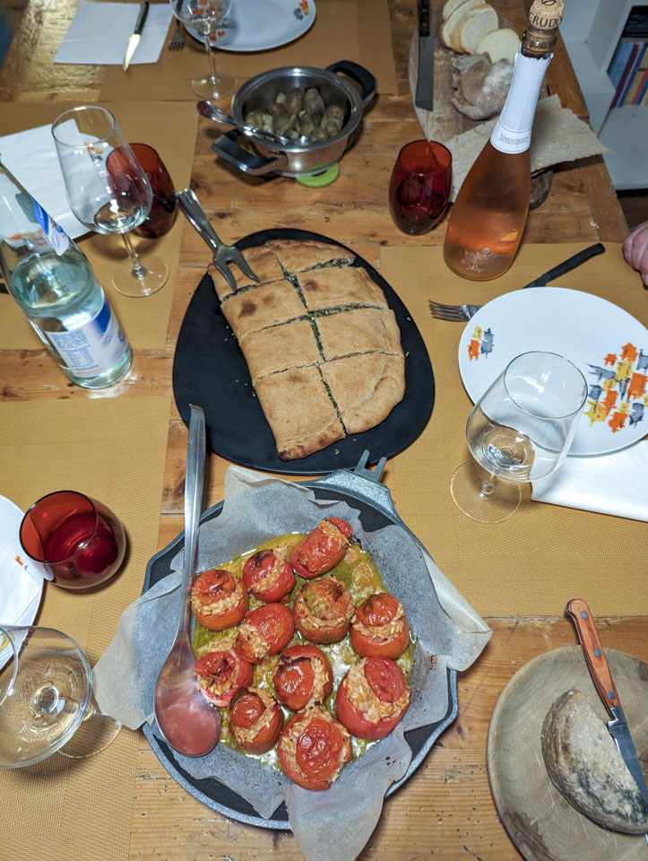 Looking down at a wooden table, there are plates of the food desribed above. The cheese wheel is over half gone.