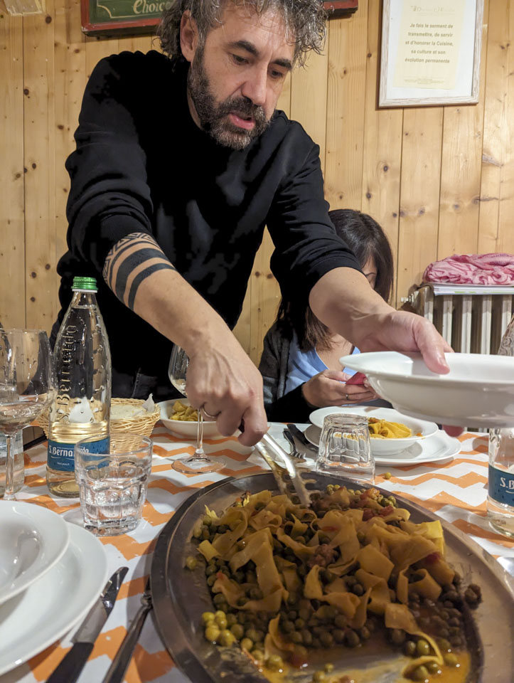 Federico is serving from a large dish that has pasta and peas.
