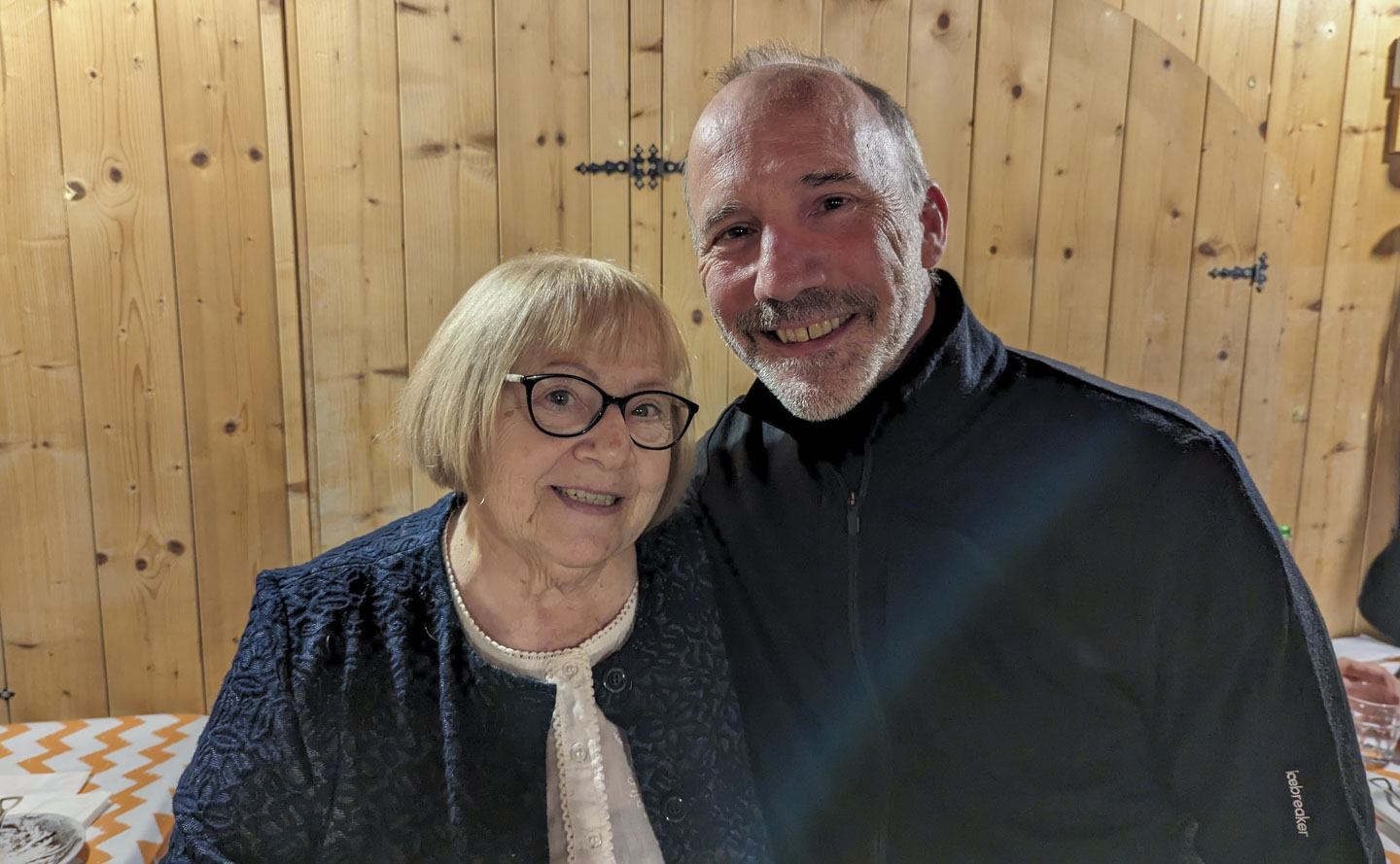 A woman with short blond hair and dark glasses standing next to Paul.