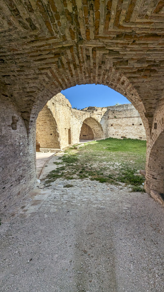 Looking down an arch-covered area into an open square, with other arches visible. The arched areas are very thick.