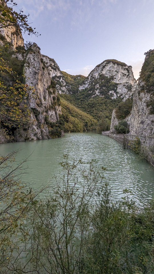 The river looks green, and the highway goes along the right side of the river with tall cliffs on both sides.