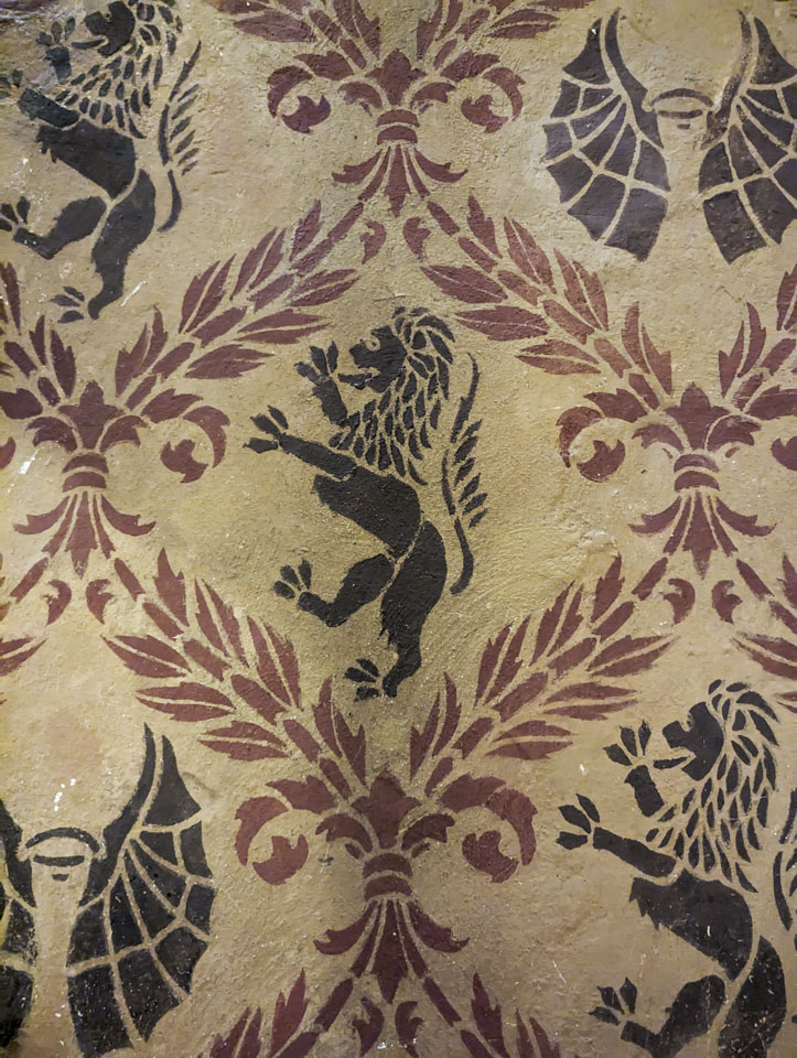 Decorative lions and dragon wings with red decorative wheat sheafs creating a pattern between them,