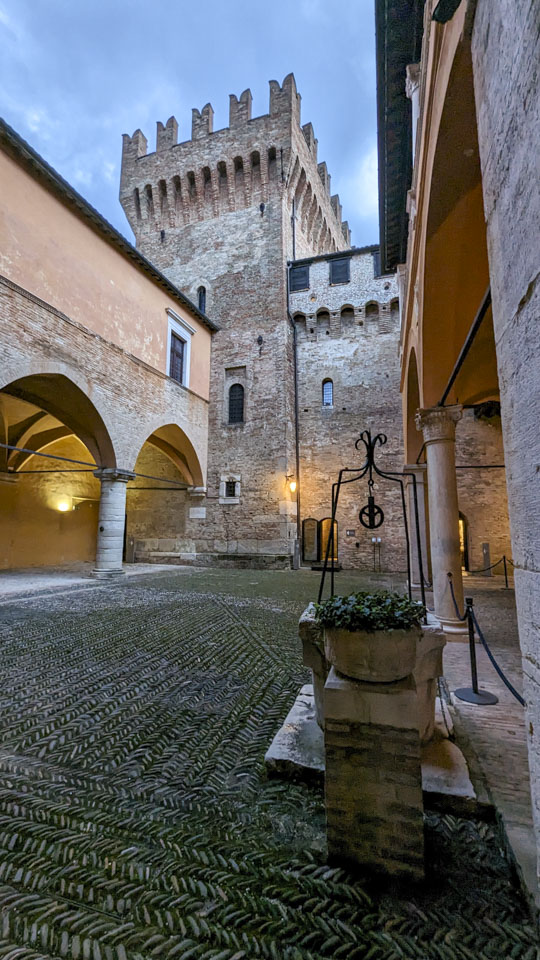 Courtyard area with an interestingly patterned floor, a castle tower, and a plant.
