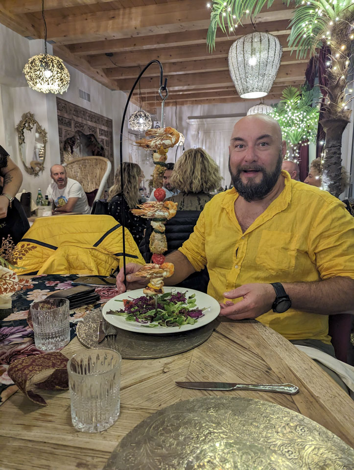 Filippo with a vertical skewer of seafood in front of him.