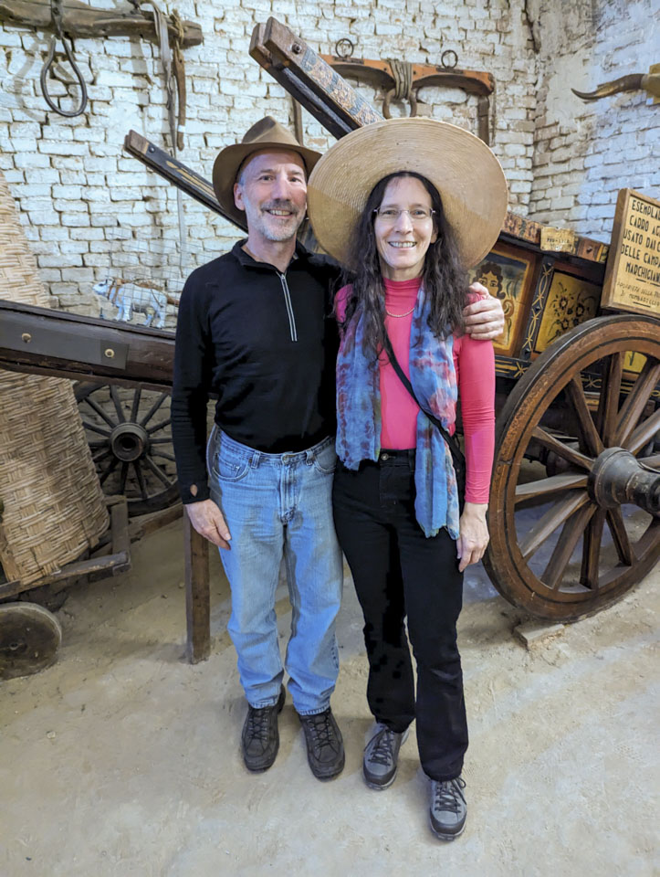 Paul and Anne standing in front of the ornate carriage. Paul has a small hat one and Anne is wearing a very large brimmed hat.