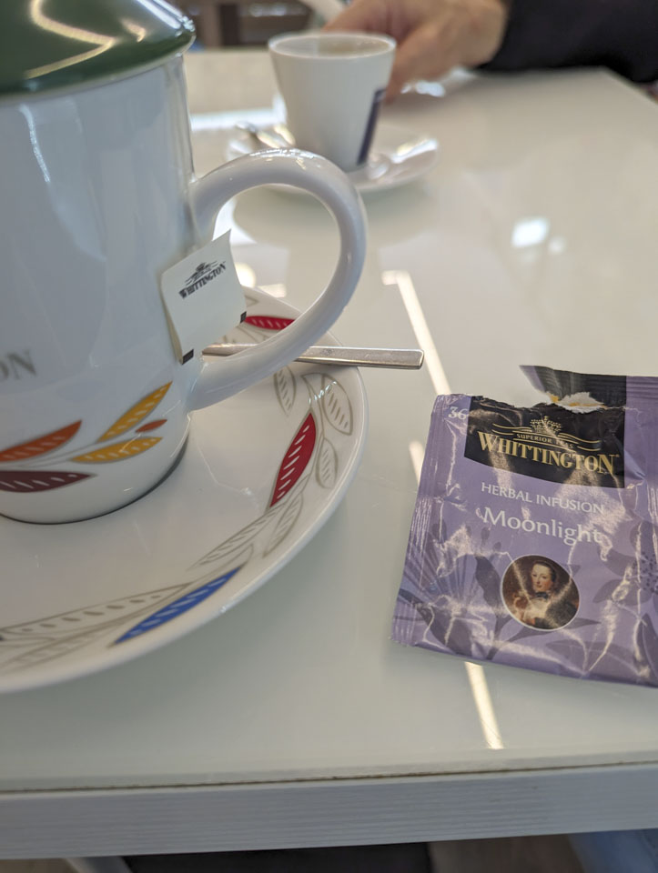 A teacup with a tea bag wrapper next to it.