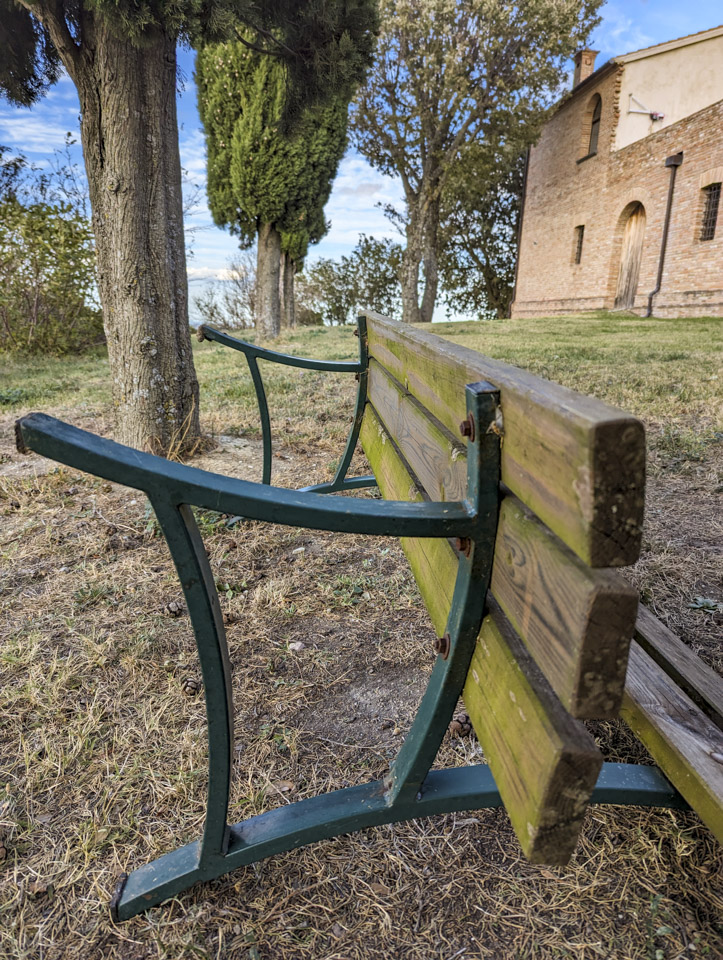 An outdoor bench that is tipped over so the backrest is against the ground.