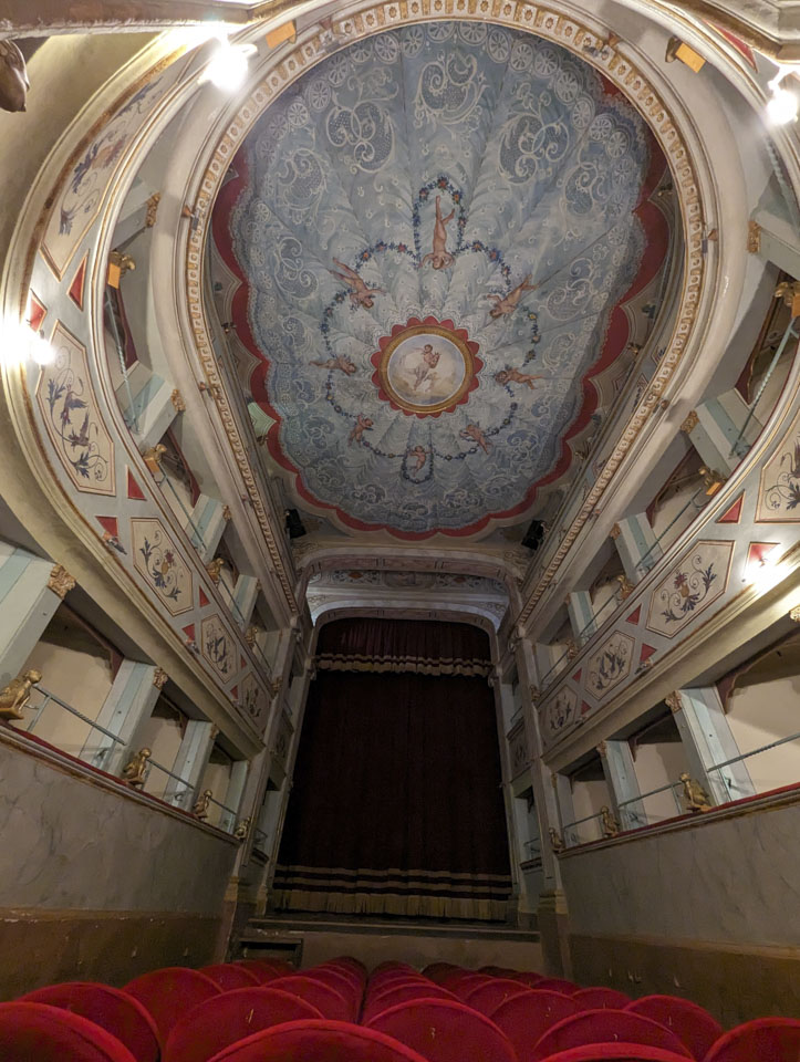 Wide-angle view inside Apollo Theater showing the stage, the ornate ceiling, box seats, and red floor seats.