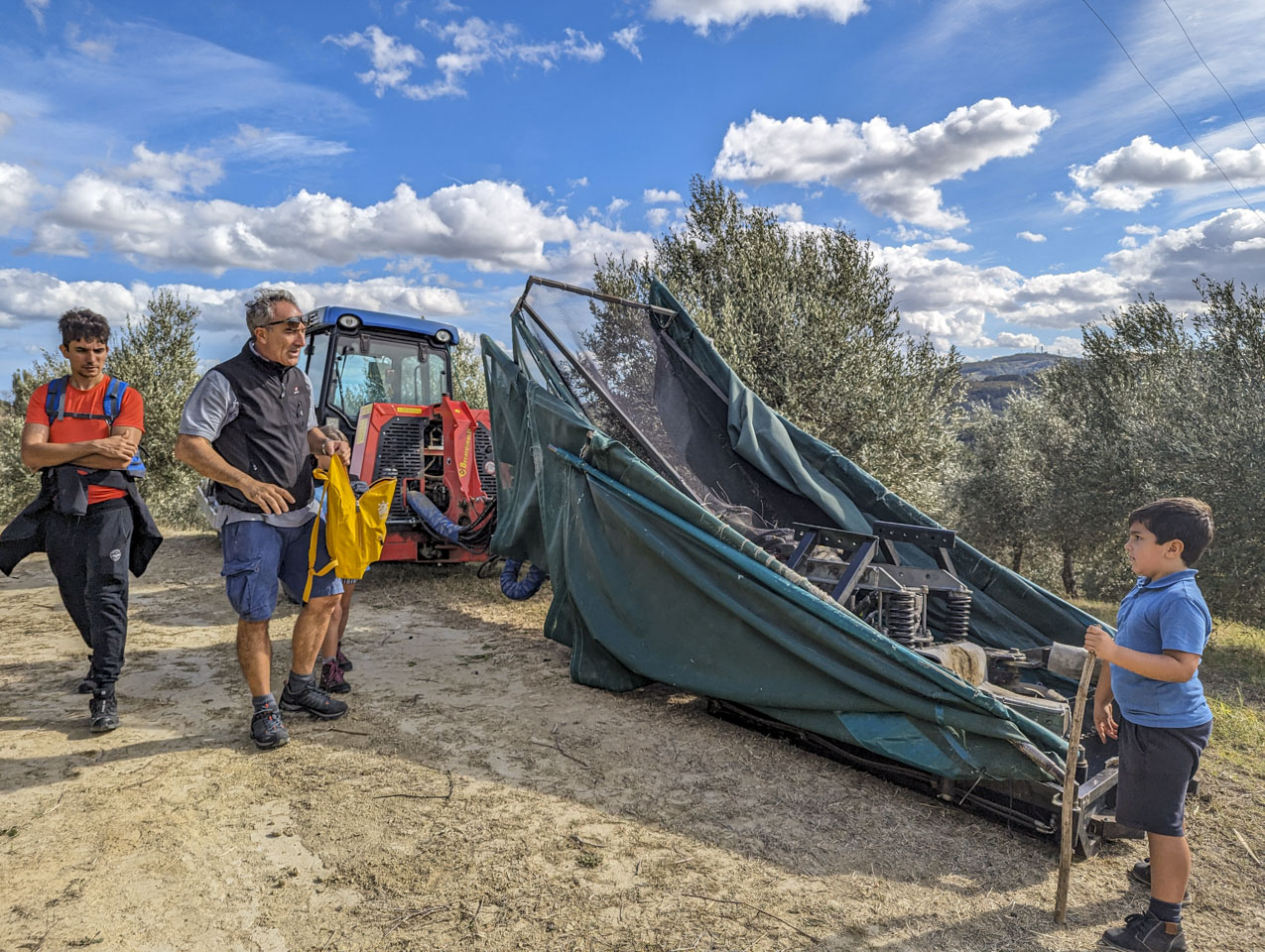 The machine described above sits in front of olive trees.