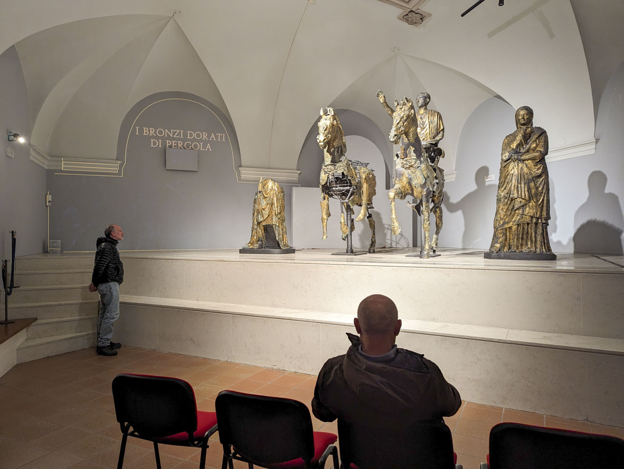 Paul is standing on the left, and Francesco is sitting on the right. Both are looking at the statues described above.