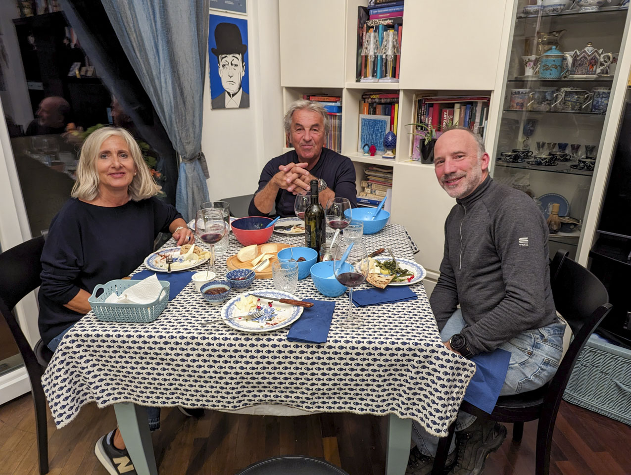 Alizia, Roberto, and Paul sit at a square table with remains of food in front of them.