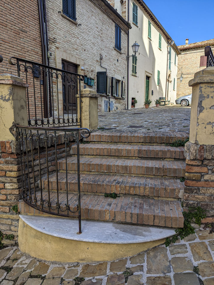 A short brick staircase with a curved railing on one side. 
