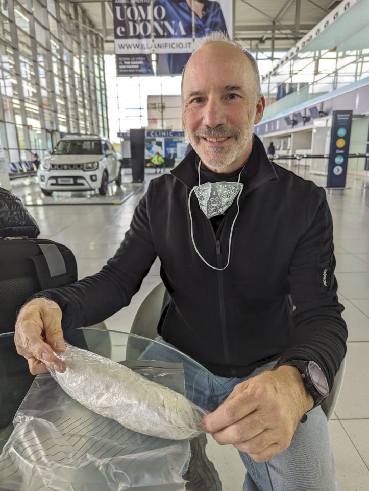 Paul sitting at a glass table with a wrapped sandwich.