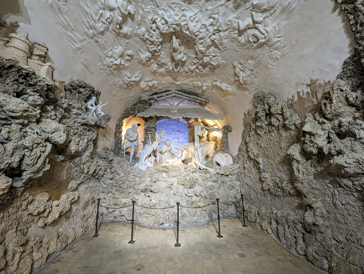 A view of the room described above. The ceiling have relief sculptures of angels. There are small figures on the rocks of the walls, and a model of what is likely urbino can also be seen along the wall.