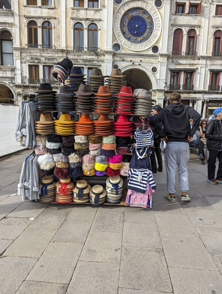 A vendor stand that has various felt hats, straw hats, and insulated hats.