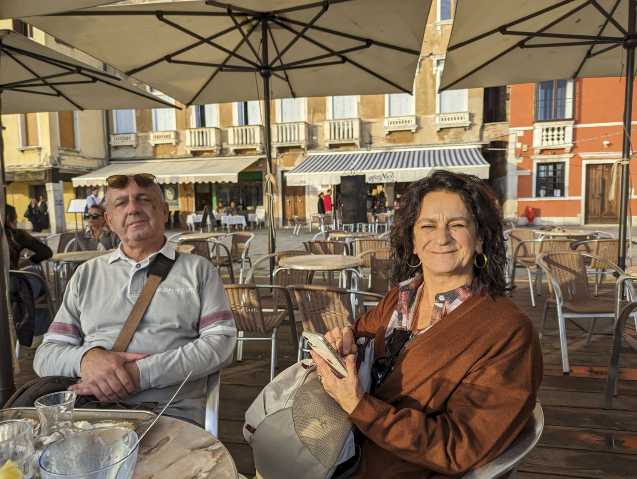 Francesco and Doni with the evening sun shining on them and empty dishes of gelato ice cream on the table.