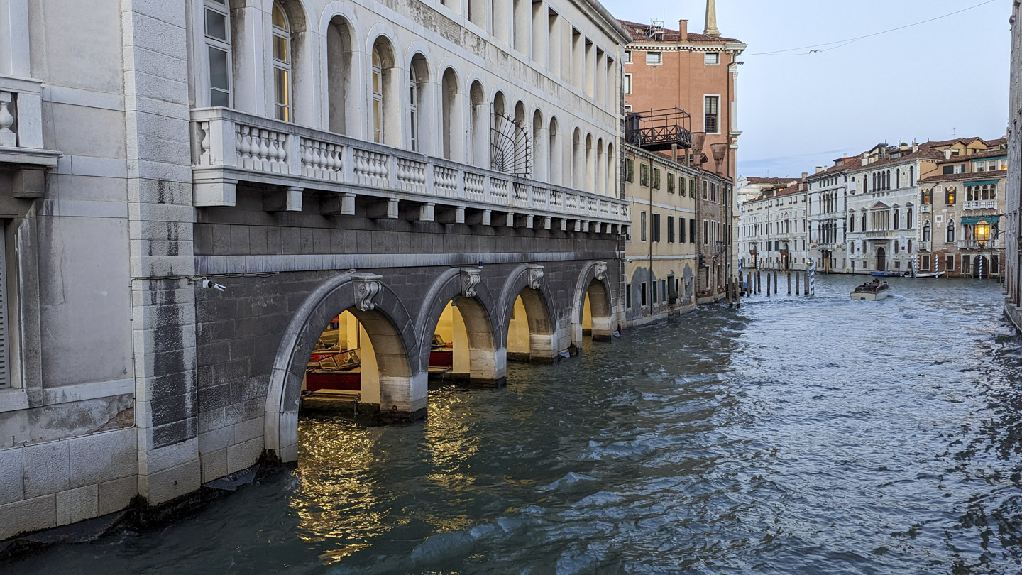 View of a canal with four arched openings to boat slips. Red boats that are used to fight fires can be seen in the slips.