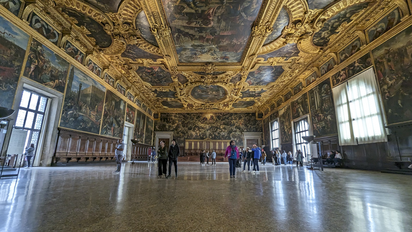 A view of the Great Council room of the Doge Palace. The walls and ceilings are covered with paintings and gold trim.