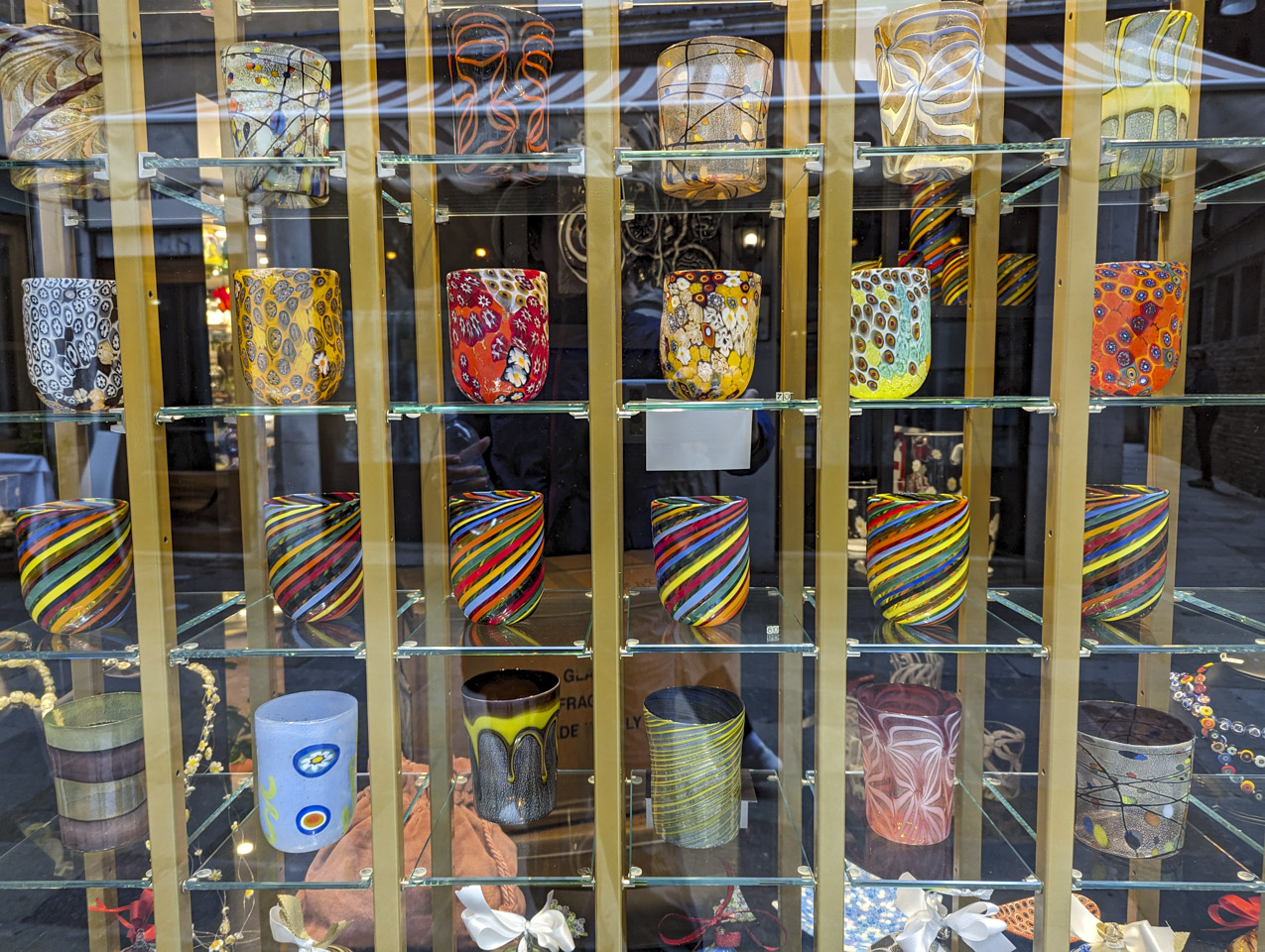 A window display of various types of Murano Glass glasses, with many different color configurations.