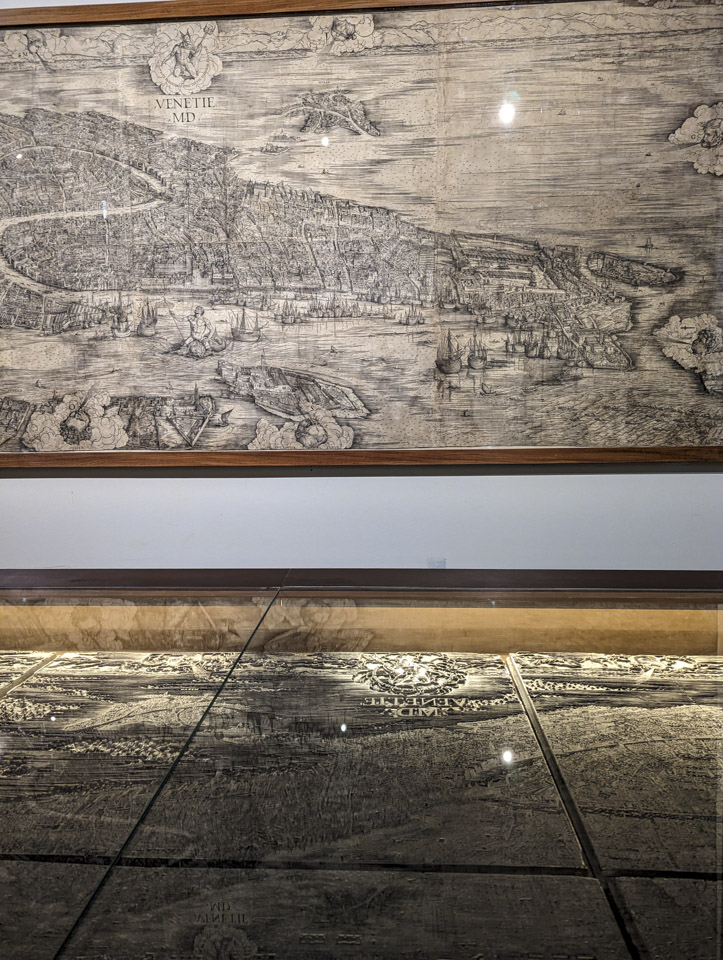 A black and white print of Venice on the wall, and a case holding the printing plates used to make the print.