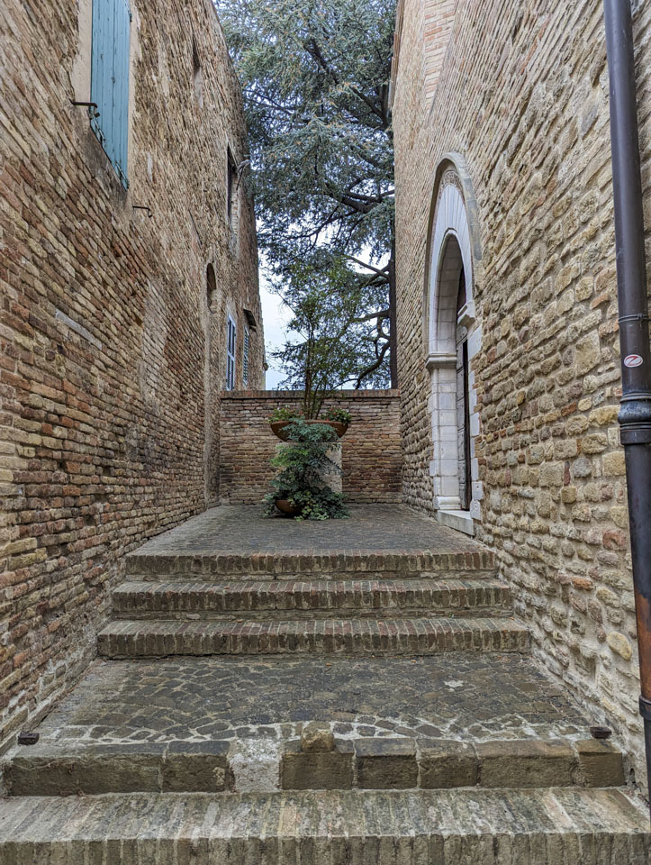 A few steps up to a landing with a large plant, and the door to the church is on the right of the photograph