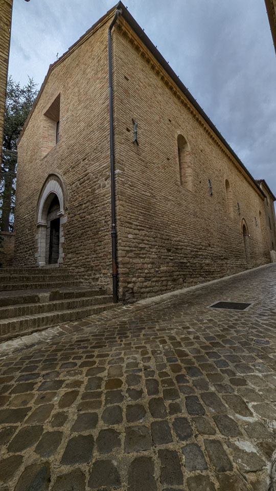 outside Chiesa di San Michele, stone and brick with some windows and a small cross above the church