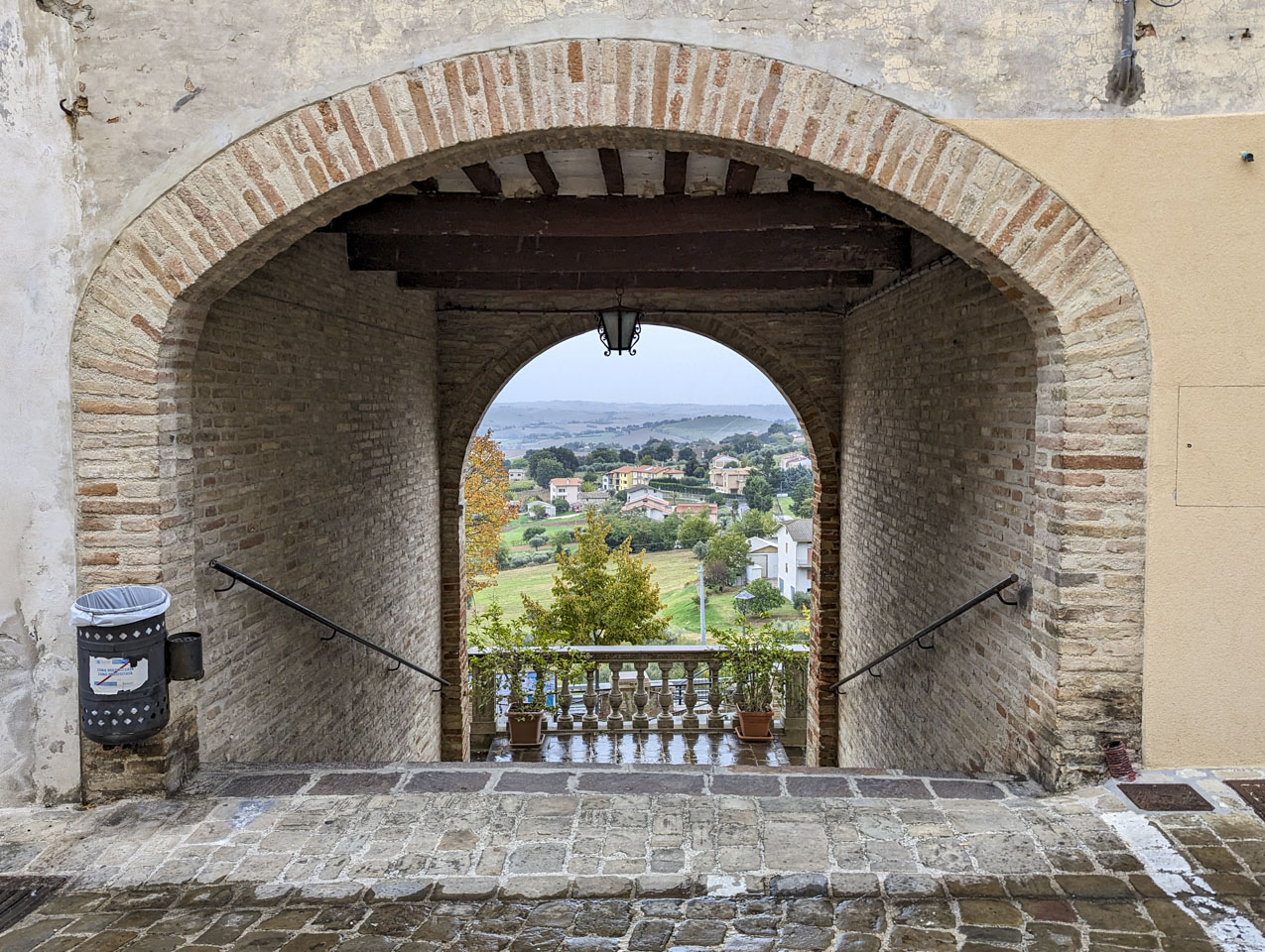 view through an arched stairway of some houses and farmland 