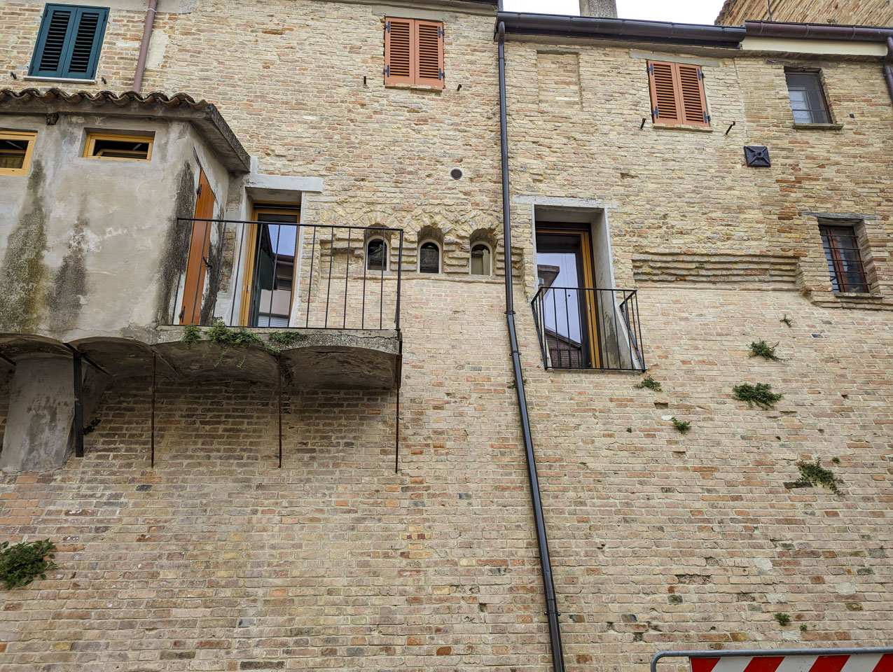 An old medieval wall with a concrete storage room sitting on the outside of the wall.