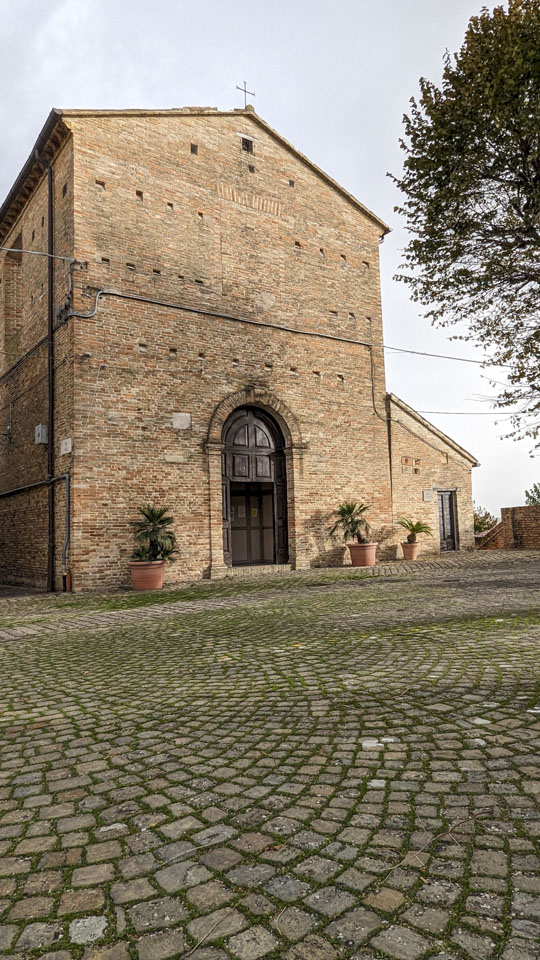 Stone paving with a plain front church on the far side.