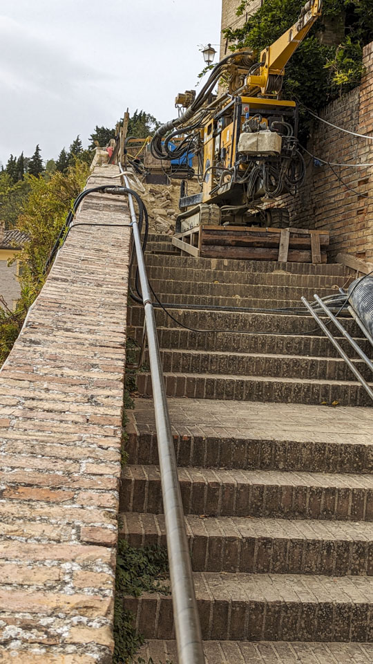 A view of the stairs on top of the wall, and a piece of machinery. They have placed a wedge-shaped platform underneath the machine to give it stability on the stairs.