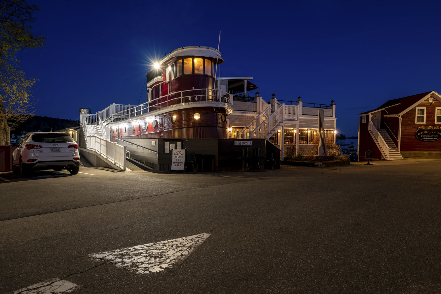 Tugboat Inn seen after sunset, with lights on and a dark blue sky behind it.