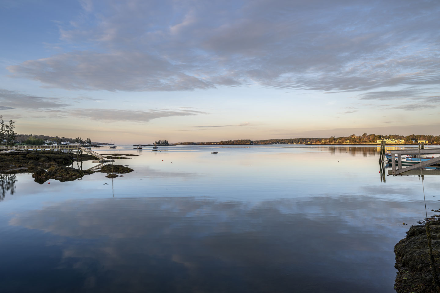 A large expanse of water that has the clouds reflected in it, and piers on each side of the picture.