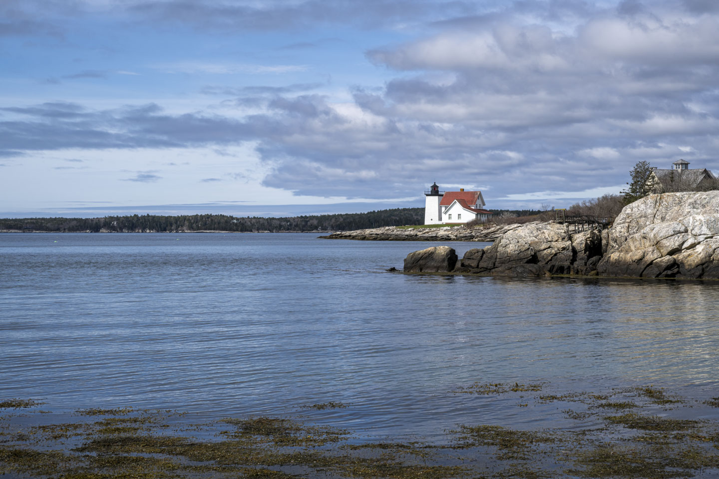 A closer view of Hendricks Head Lighthouse, with a square tower, white walls, and a red roof.
