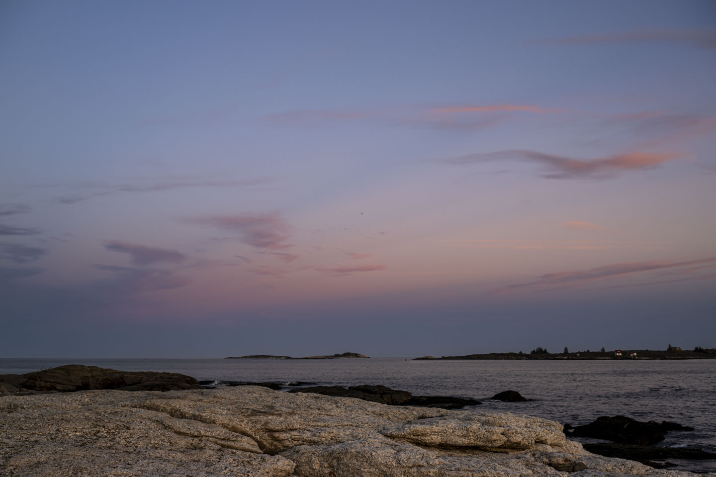 Sky Blue Pink above, rocks and water below.