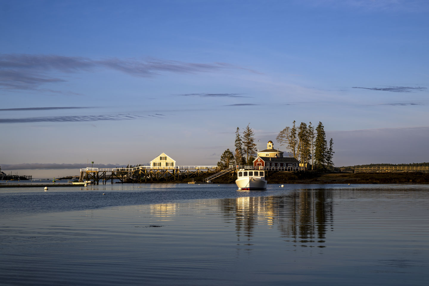 McFarland Island at sunrise. A boat is in the water facing us. The 3 residences of the island cam be seen.